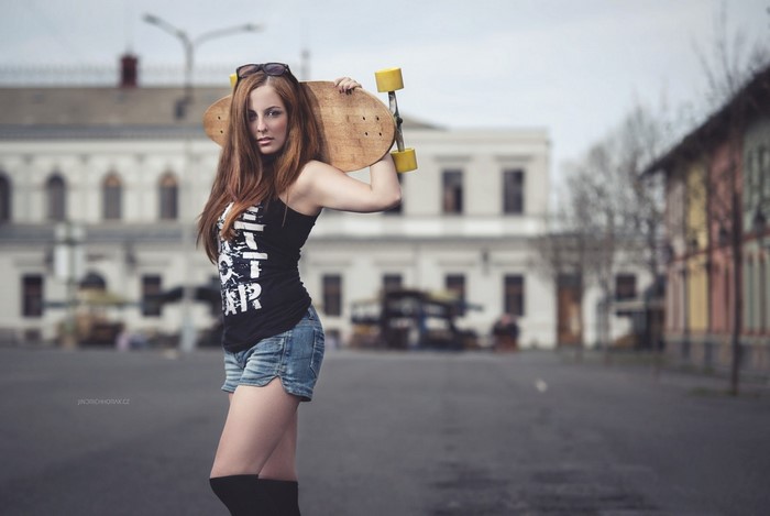 Confident Woman with Skateboard in Urban Setting