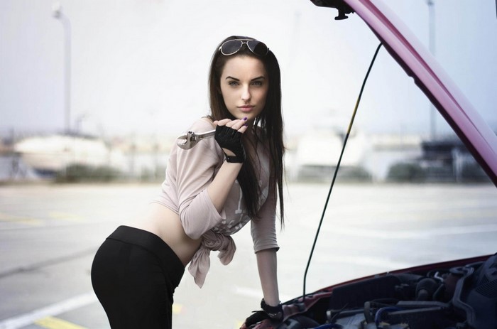Woman with wrench by car engine
