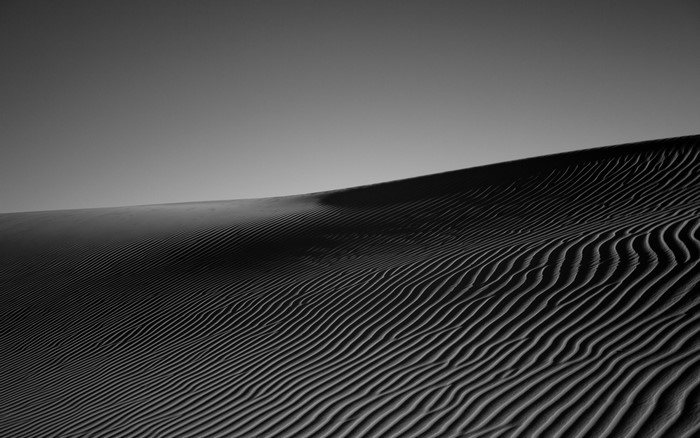 Monochrome image of sand dunes with rippled patterns