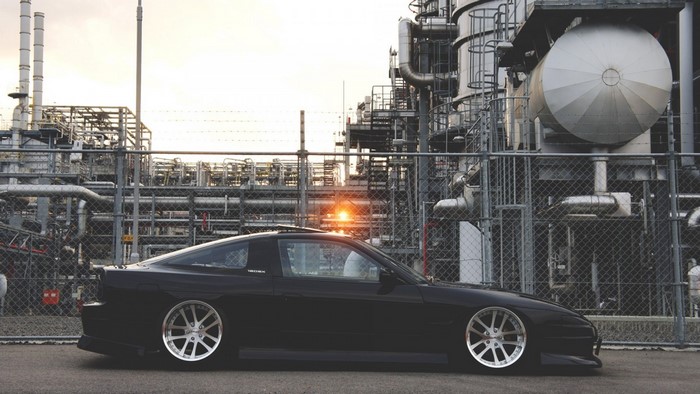 Black Nissan 180SX parked at industrial facility