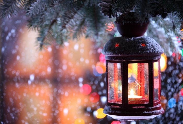 Christmas lantern with candle on a snowy pine branch