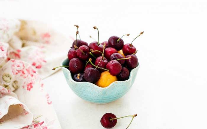 Cherries in a blue bowl with a floral cloth