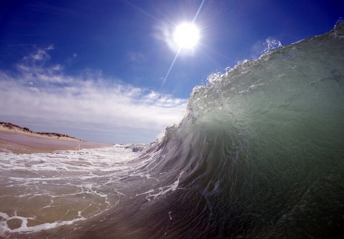 Wave crashing on a sandy beach under the sun