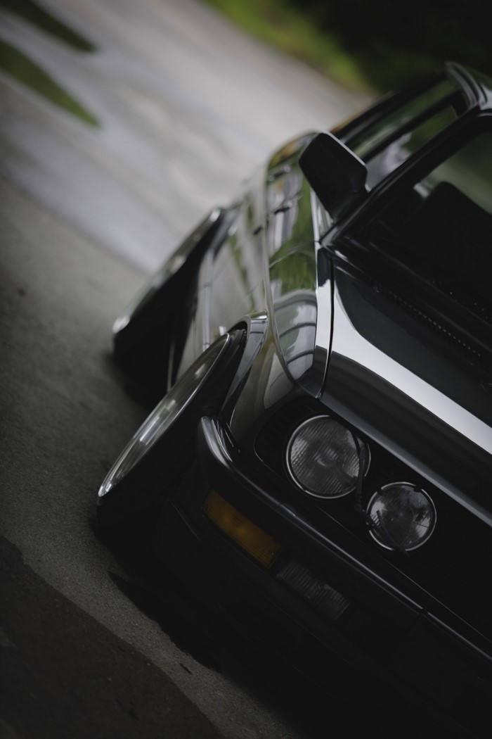Black BMW E28 with lowered stance on a wet road