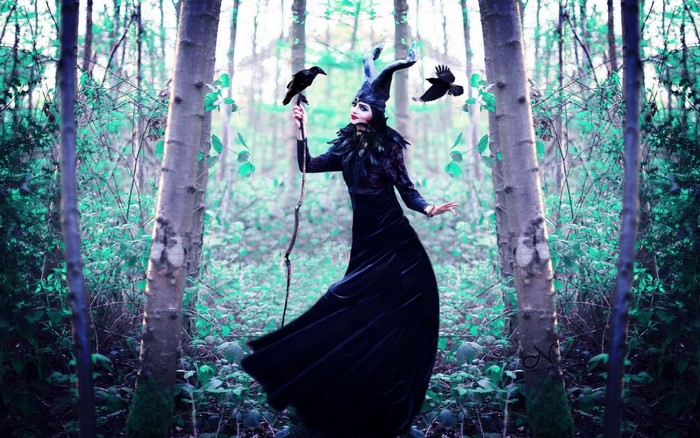 Woman in Maleficent cosplay with crows in a forest