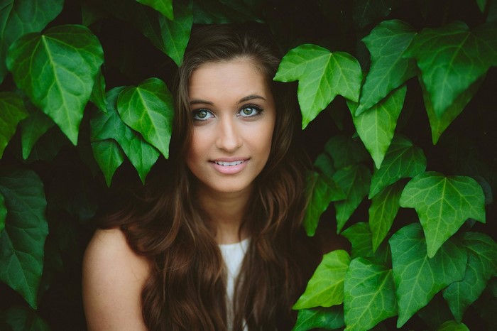 Woman with green eyes surrounded by green leaves