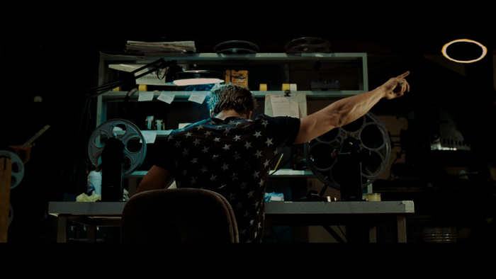 Man in star shirt pointing in a dark room with film reels