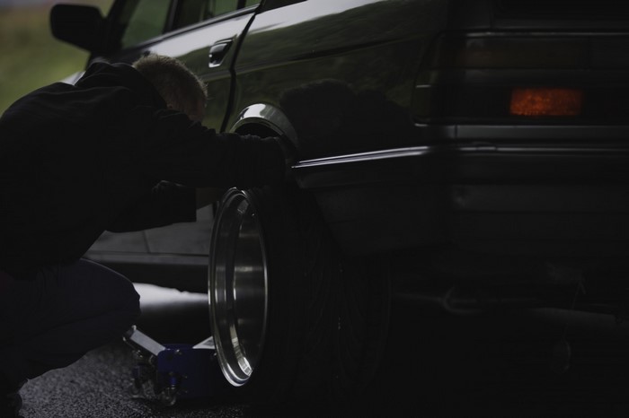 Person changing tire on a black BMW E28