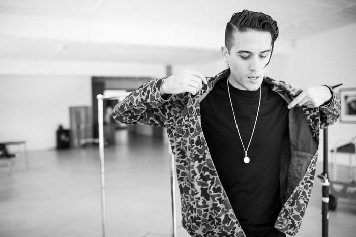 G-Eazy putting on a camouflage jacket