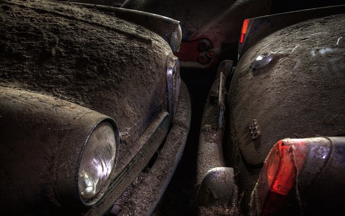 Dusty abandoned cars in a dark garage