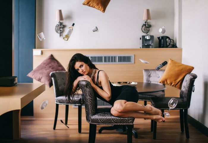 Woman in Black Dress Reclining on Chair in Modern Room