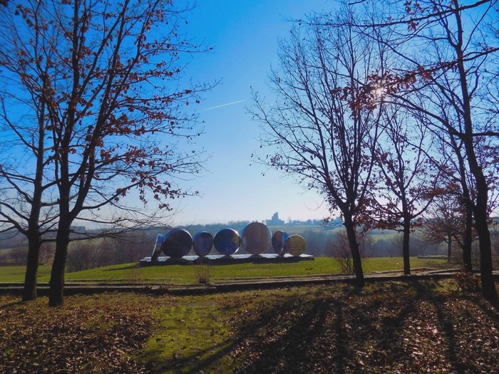Sculpture in a park with trees and a distant building