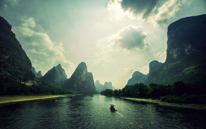 River flowing through karst mountains under a cloudy sky