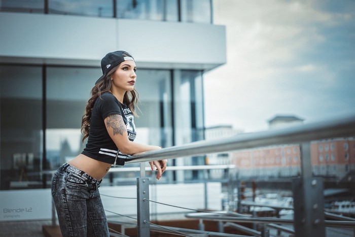 Woman in baseball cap and jeans posing outdoors