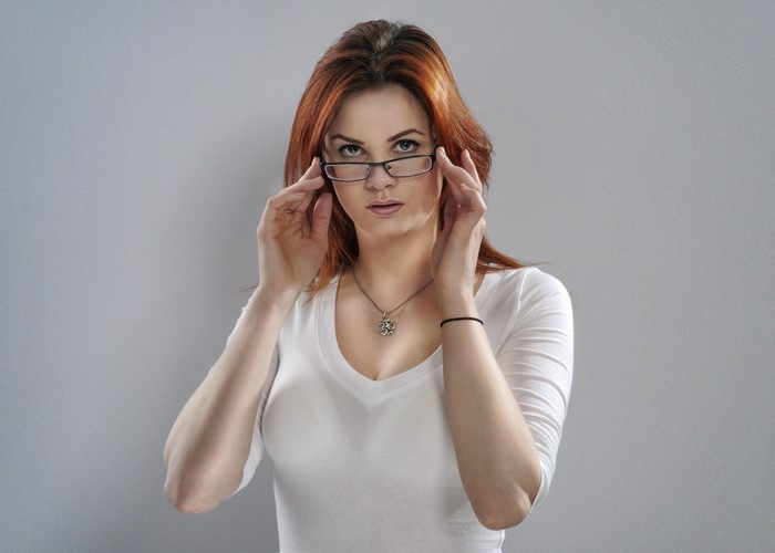 Woman with red hair wearing glasses and white shirt