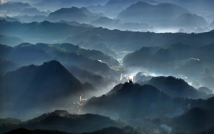 Misty mountain valley at sunrise with a village