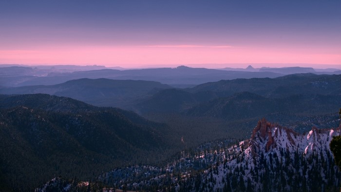 Mountain valley at sunset with snow-capped peaks