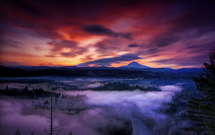 Misty valley with snowy mountain peak at sunset