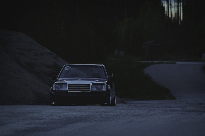 Black Mercedes-Benz E-Class parked on a dirt road at dusk