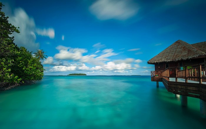 Overwater bungalow on turquoise water with island in distance