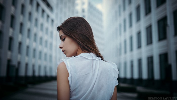 Woman in white top standing between buildings