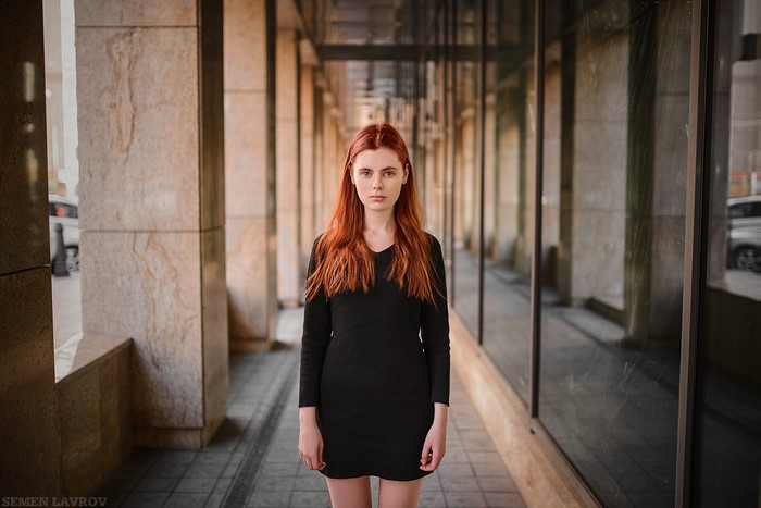 Redhead woman in black dress standing in a hallway