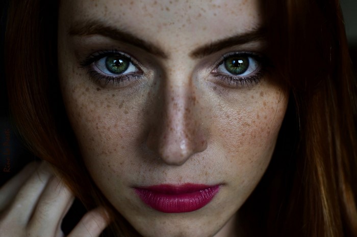 Close-up portrait of a woman with freckles and green eyes