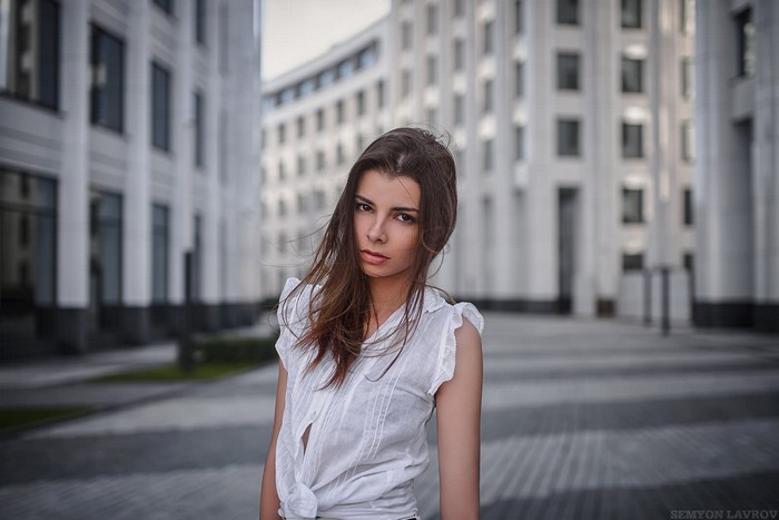 Woman in white top standing in front of modern buildings