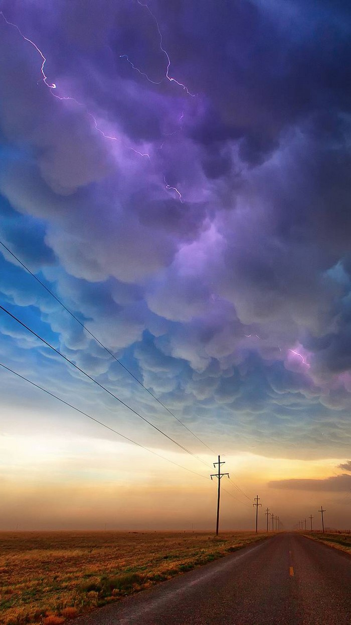 Lightning storm over a prairie road at sunset
