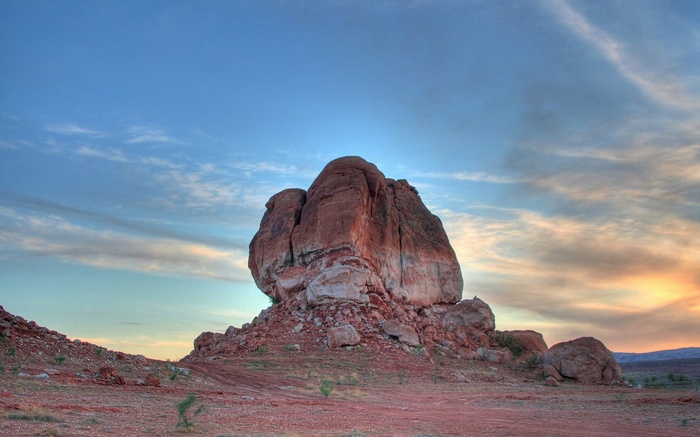 Large rock formation in a desert landscape at sunset