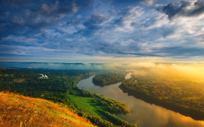 River valley with mist and sunrise over hills