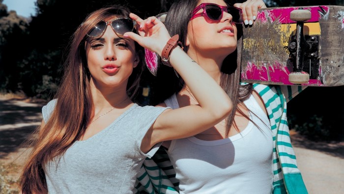Two young women with sunglasses and a skateboard
