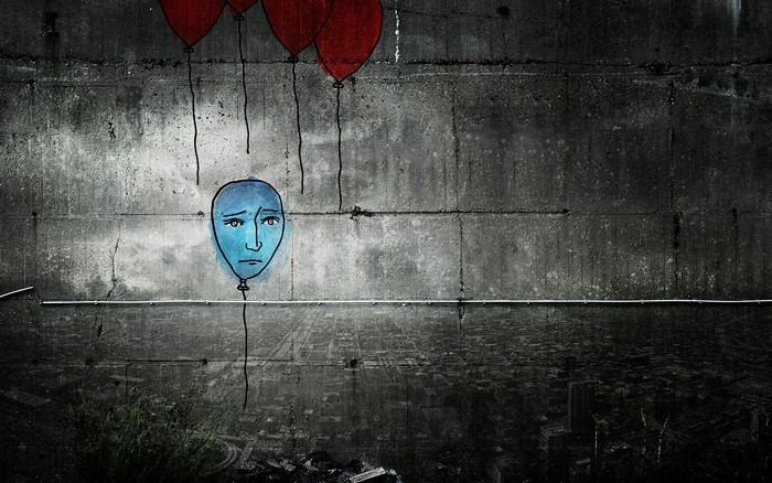 Sad blue balloon face graffiti on concrete wall