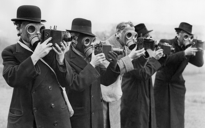 Men in gas masks holding cameras