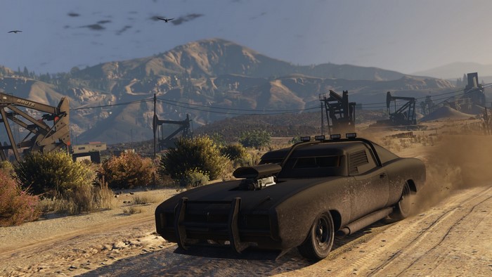 Customized car driving on a dirt road in a desert landscape