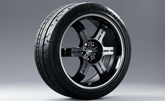 Black alloy wheel with a tire on a gray background