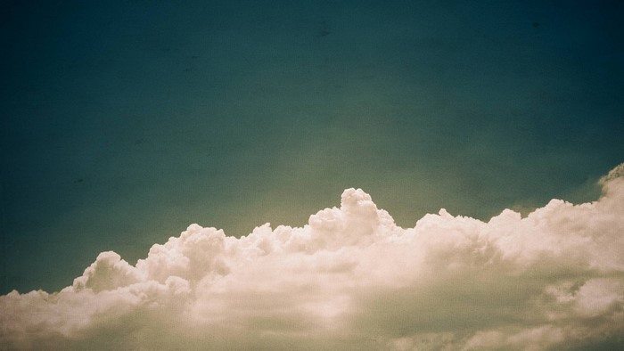 Cumulus clouds against a dark blue sky