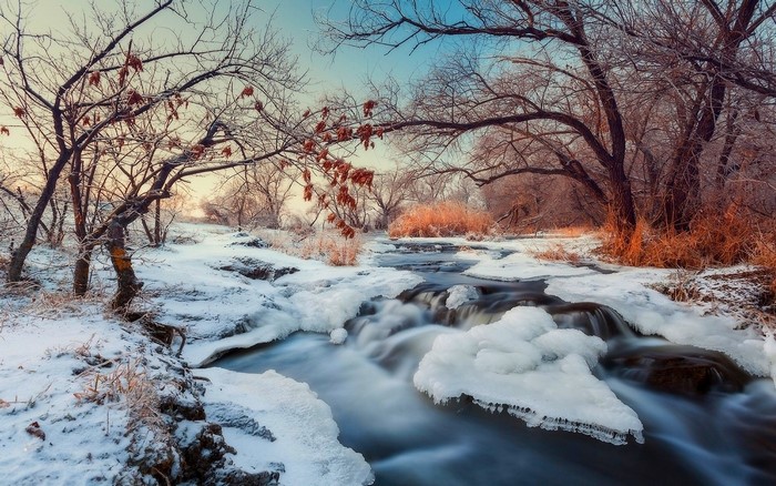 Winter stream with ice and snow at sunrise