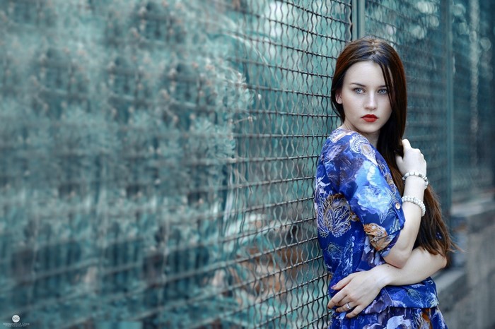 Woman with long brown hair and blue eyes wearing a blue dress