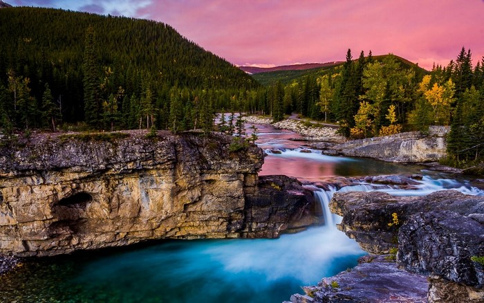 Waterfall in a forest valley during autumn sunset