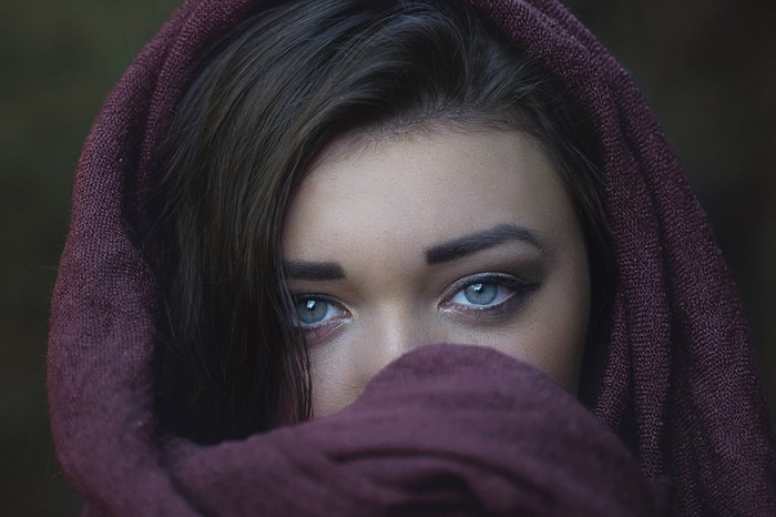 Woman with blue eyes and dark hair wearing a purple scarf