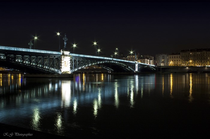 Bridge over river at night with city lights reflection