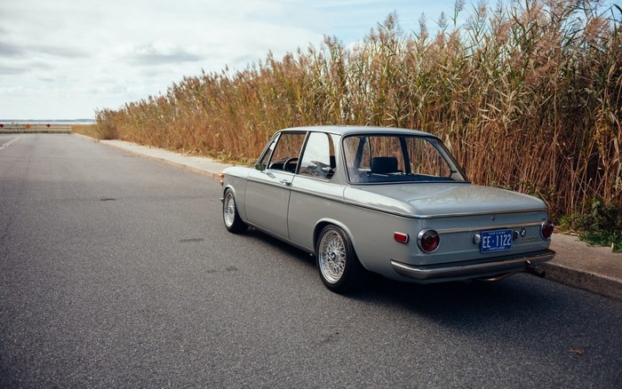 Gray BMW 2002 parked on a road with tall grass