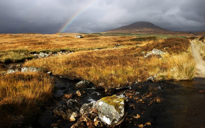 Rainbow over a Scottish Highland landscape with a stream