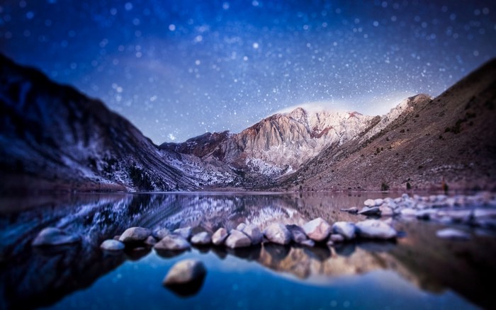Mountains reflected in a lake under a starry night sky