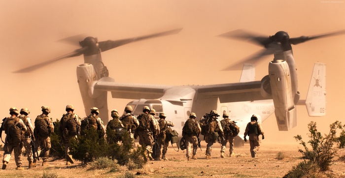 Marines disembarking from a Bell V-22 Osprey in a desert