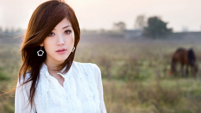 Woman with long brown hair in a white shirt outdoors