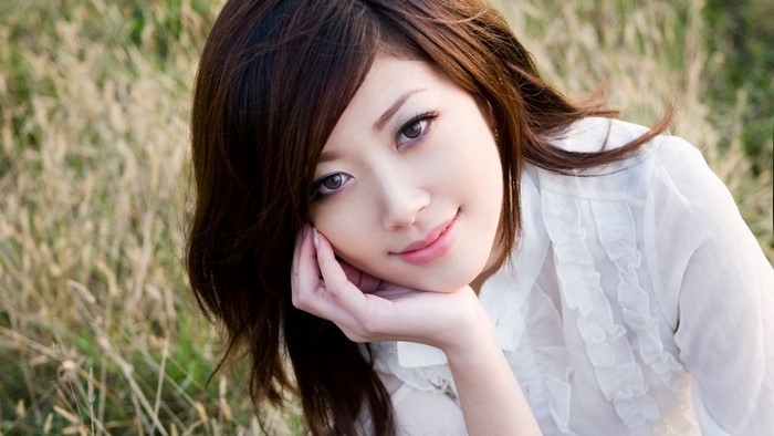 Asian woman with brown hair in a white shirt outdoors