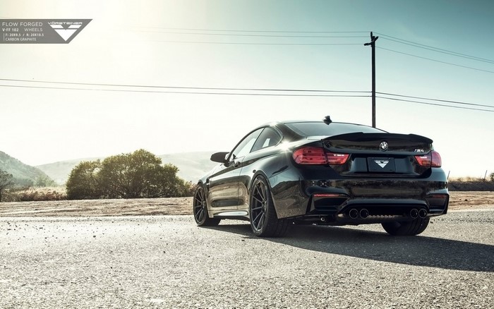 Black BMW M4 with Vorsteiner wheels on a road