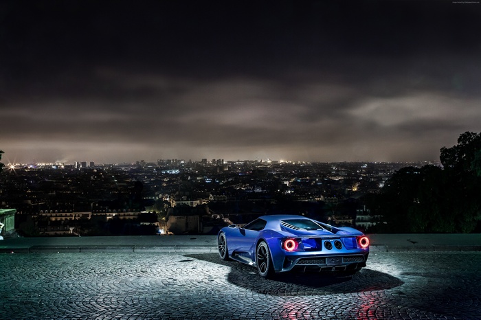 Blue Ford GT supercar parked overlooking a city at night